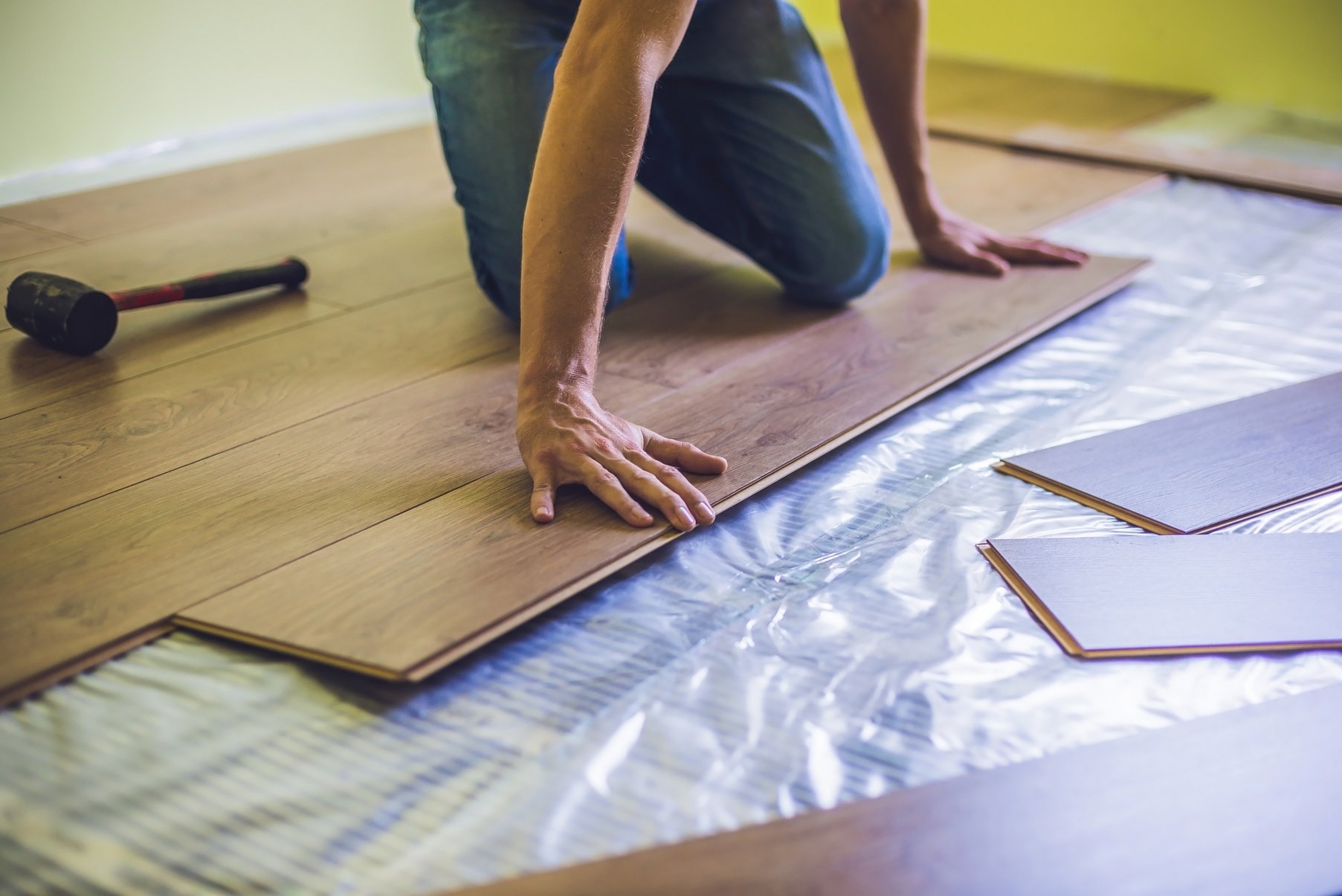 Man Installing New Wooden Laminate Flooring. Infrared Floor Heating System under Laminate Floor